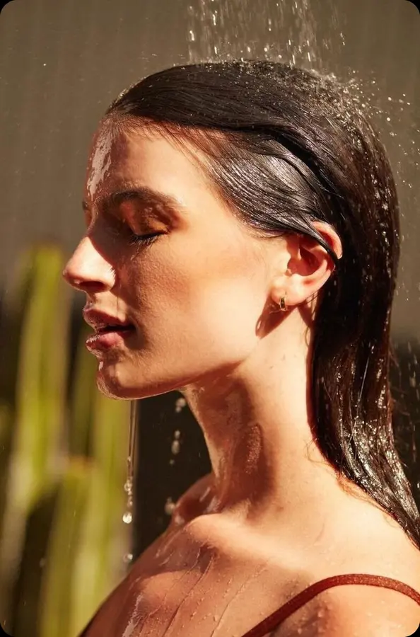Woman rinsing hair under soft, filtered rainfall